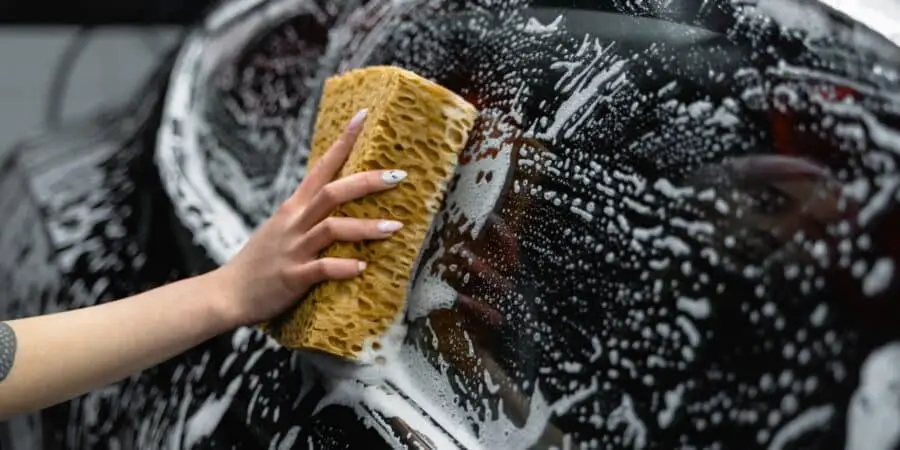 photo of a person cleaning the window of a black car